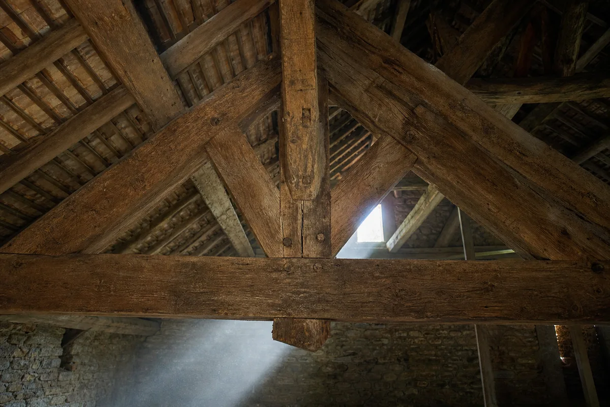 Charpente traditionnelle en chene apparente dans les combles d’une maison ancienne