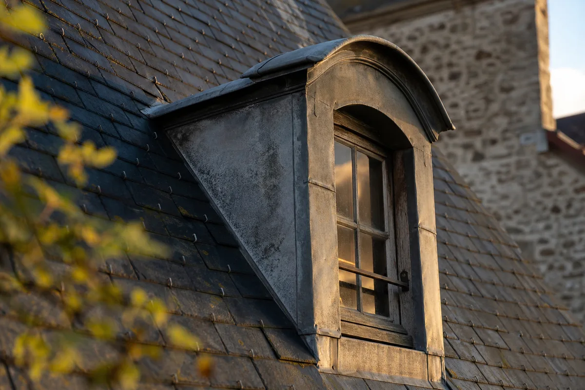 Détail d’une lucarne en zinc et ardoise sur un toit ancien des Yvelines